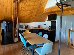 eine Küche mit einem Holztisch und blauen Stühlen in der Unterkunft La Tanière in Vaujany