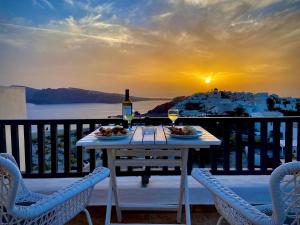 stół z dwoma talerzami jedzenia i butelką wina w obiekcie Aspa Villas w mieście Oia