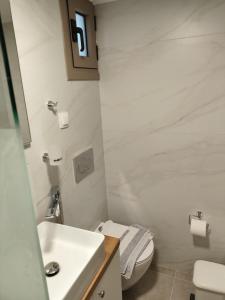 a white bathroom with a toilet and a sink at Protopapas in Palaiochora