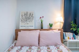 ein Bett mit rosa Kissen und einem Bild an der Wand in der Unterkunft Stay CarpeDiem Hannam in Seoul
