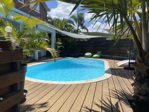 a swimming pool in a yard with a wooden deck at P'ti coin zen in Saint-Gilles-les-Bains