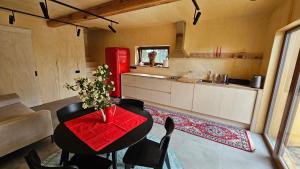 a kitchen with a table with chairs and a red table cloth at Kur skamba varpai in Berżory