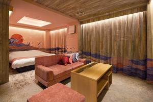 にある弥富ホテルヌク全室天然温泉のベッドルーム1室(ベッド1台、ソファ、椅子付)