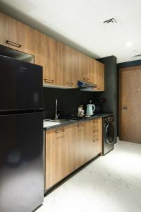 a kitchen with wooden cabinets and a black refrigerator at Industrial Chic Retreat in Al Qurayyah