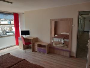 a room with a bedroom with a mirror and a desk at Стаи за гости Първи май in Gabrovo