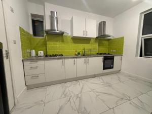 a kitchen with white cabinets and green tiles at PRIVATE ROOM In TOWN CENTRE FREE PARKING WI FI AND PATIO WITH AA STAY LTD in Buckinghamshire