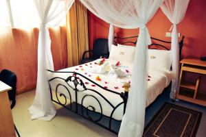 Un dormitorio con una cama blanca y negra con flores. en Wagon Wheel Hotel Eldoret en Eldoret