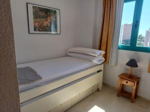 małe łóżko w pokoju z oknem w obiekcie Precioso apartamento con piscina cerca de la playa w mieście Benidorm +5 zdjęć
