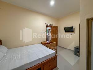 a bedroom in a house with a bed and a tv at Ndalem Joglo Kawijayan Syariah Mitra RedDoorz in Kadipiro +20 photos