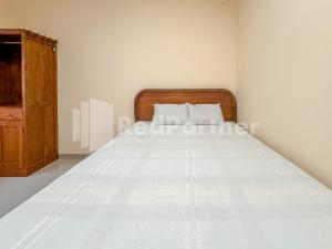 a bedroom with a bed with a wooden headboard at Ndalem Joglo Kawijayan Syariah Mitra RedDoorz in Kadipiro