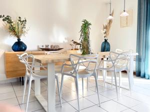 a dining room with a wooden table and white chairs at Les Vigies-T4 au calme-vue mer-terrasse-Parking in Collioure +30 photos