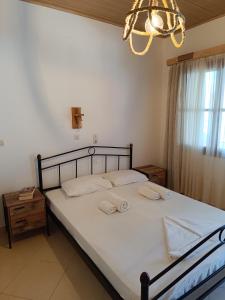 a bedroom with a bed with white sheets and a chandelier at Athina Studio Apartments in Kerveli