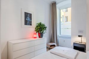 ein weißes Schlafzimmer mit einer Pflanze auf einer Kommode in der Unterkunft Urban Smart Kreuzberg in Berlin