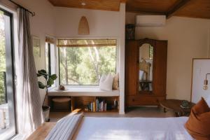 1 dormitorio con ventana, cama y espejo en Treetop Tranquility, en Opua