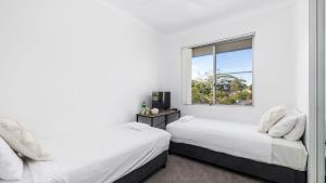 two beds in a room with a window at Beachside at Gretel in Nelson Bay