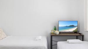 a bedroom with two beds and a tv on a table at Beachside at Gretel in Nelson Bay +16 photos