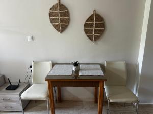 einen Esstisch mit 2 weißen Stühlen und einem Tisch in der Unterkunft Central House Karistos in Karystos