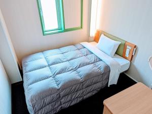Dormitorio pequeño con cama azul y almohada en R&B Hotel Morioka Ekimae, en Morioka