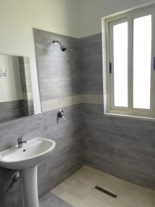 uma casa de banho com um lavatório branco e uma janela em LUMNIK - Hotel & Apartments em Lezhë