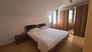 um quarto com uma cama grande e lençóis brancos em Classic Apartament em Buzau