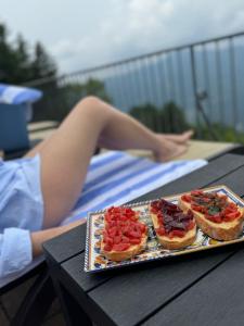 Dos pizzas en una bandeja en una mesa con una mujer en una mesa en Hotel Paradiso Como, en Brunate