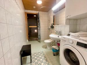 a bathroom with a washing machine and a sink at Kotimaailma Apartments Lahti in Lahti