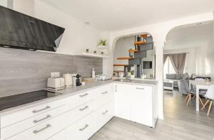 a kitchen with white cabinets and a living room at Maisonnette avec terrasse in Strasbourg