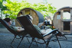 two boys sitting in chairs in front of some barrels at LUONTE 霧の高原 Glamping 