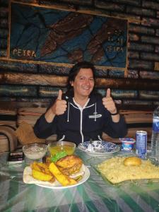 a man giving thumbs up while sitting at a table with food at Petra Anas House in Wadi Musa