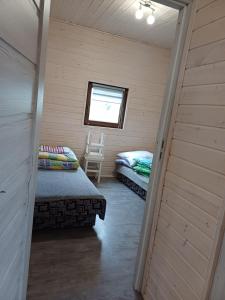 Una pequeña habitación con dos camas y una ventana. en Wichrowa Skarpa, en Rusinowo