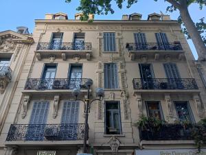 a tall white building with balconies and a street light at Maison Carnot in Cannes