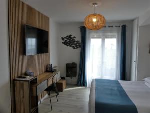 um quarto com uma cama, uma secretária e uma televisão em Hôtel de la Vierge Noire em Sainte-Maxime