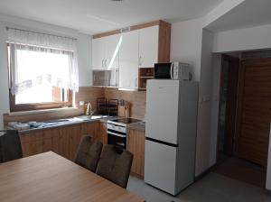 a kitchen with a white refrigerator and a table at Domki u Eweli CAŁOROCZNE ogrzewane kominkiem in Stegna