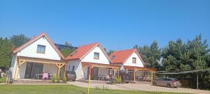 two houses with red roofs in a yard at Domki u Eweli CAŁOROCZNE ogrzewane kominkiem in Stegna