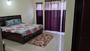 1 dormitorio con 1 cama con cortinas moradas y alfombra en Vrinda Homestay, en Vrindāvan