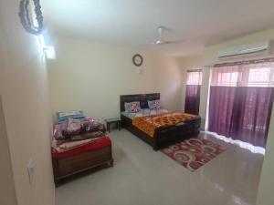 Un dormitorio con dos camas y dos otomanas. en Vrinda Homestay, en Vrindāvan