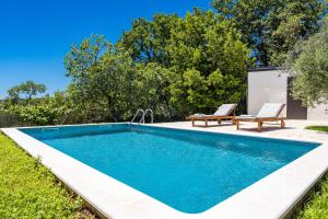 a swimming pool in the yard with two benches next to it at Casa Mirna for 7 people near Pula with sea view & only 2 km from the sea in Peruški