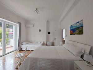 a white bedroom with a large bed and a window at Casa Ferraro in Marina Grande di Capri
