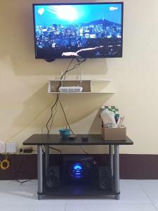 einen an einer Wand hängenden TV mit einem Tisch und einem Tisch in der Unterkunft Condo for Rent - Cagayan de Oro in Cagayan de Oro