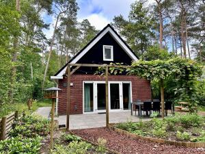 a small house with a black roof and a patio at Vakantiehuis Vliegend Hert Veluwe in Nunspeet