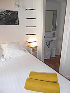 a bedroom with a white bed with a yellow seat at L'Hostalet de Cadaques in Cadaqués