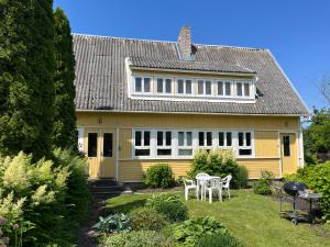 a yellow house with a table and chairs in the yard at Aliise Garden Guesthouse in Pärnu