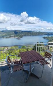 a table and chairs on a balcony with a view of a lake at Hotel Panoramico lago d'Orta in Madonna del Sasso