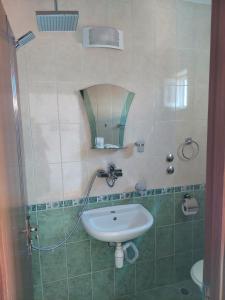 ein Bad mit einem Waschbecken und einer Dusche mit einem Spiegel in der Unterkunft Topchievi Isles in Sozopol