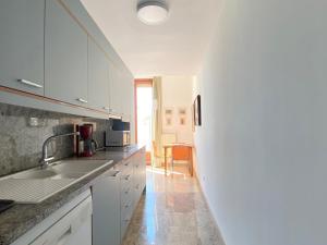 a white kitchen with a sink and a table at Exclusive Beachfront Haven in Costa Brava in Lloret de Mar +15 photos