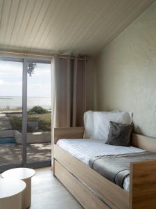 a bedroom with a bed and a view of the ocean at Hotel Punta Lara Noirmoutier - Vue Mer - Nouvellement rénové in La Guérinière