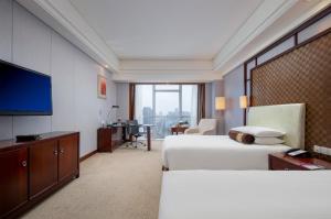 a hotel room with two beds and a flat screen tv at Haiwaihai Grand Hotel Ma'anshan in Ma'anshan