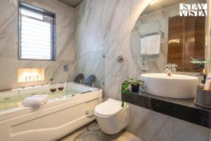 a bathroom with a sink and a toilet and a tub at StayVista at Nova Nest with Rooftop Pool in Lonavala +23 photos