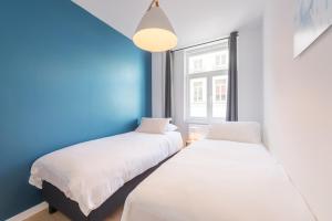 - 2 lits dans une chambre avec un mur bleu dans l'établissement Smartflats - Toison d'Or, à Bruxelles