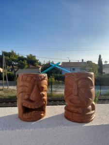 ソセ・レ・パンにあるLa locomotive - 400 m de la plageの2つの顔の木彫りがテーブルの上に置かれている